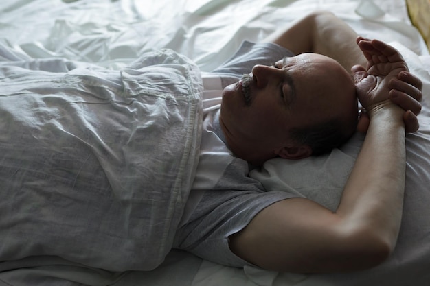 The elderly man is fast asleep covered by a white blanket Healthy sleep at night