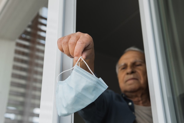 Foto l'anziano sta buttando via la maschera di prevenzione usata