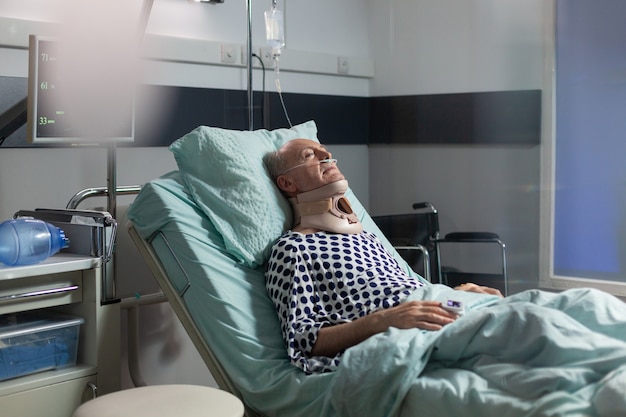 Фото Пожилой мужчина лежит в больничной койке с воротником-стойкой