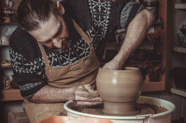 Elderly man making pot using pottery wheel 