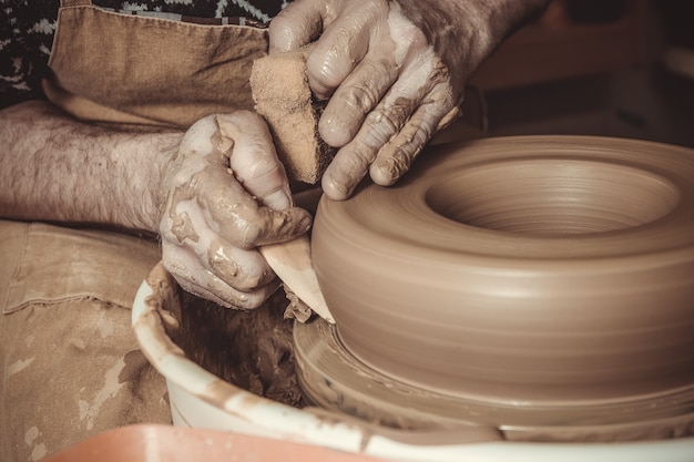 Elderly man making pot using pottery wheel 