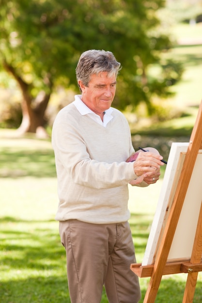 Elderly man painting in the park