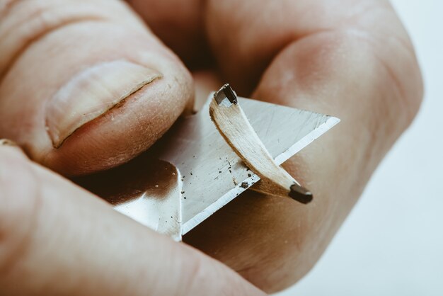 Elderly man sharpens pencil with clerical knife