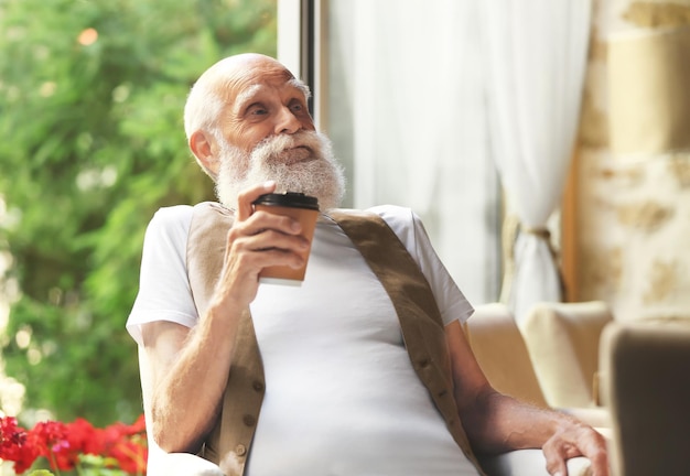 Elderly man sitting with coffee in a armchair