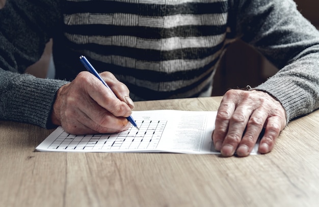 Elderly man solves sudoku or a crossword puzzle