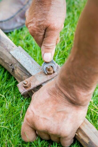 Elderly man twists the nut by wrench