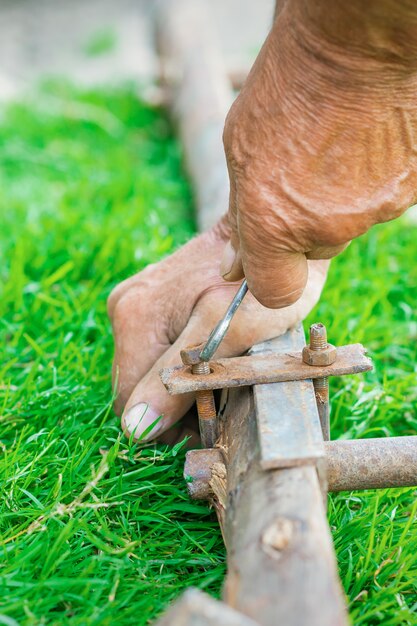 Elderly man twists the nut by wrench