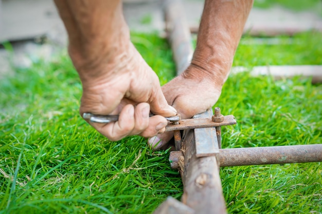 Elderly man twists the nut by wrench