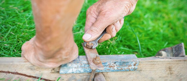 Elderly man twists the nut by wrench