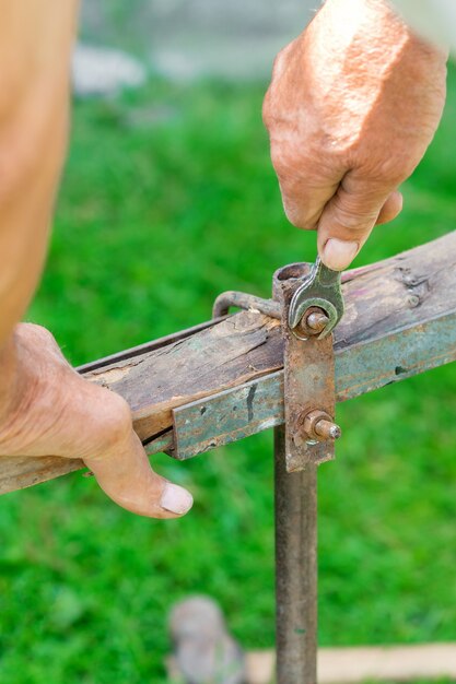 Elderly man twists the nut by wrench