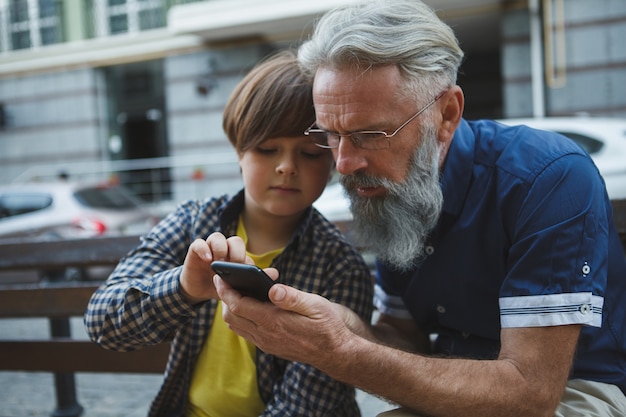 孫とスマートフォンでインターネットを利用している老人