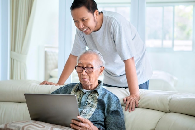 息子と一緒にラップトップ コンピューターを使用する老人