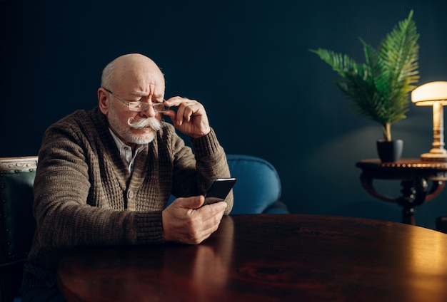 Uomo anziano utilizzando il telefono cellulare in ufficio a casa