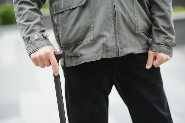 L'uomo anziano cammina con un bastone in un parco di primavera della città