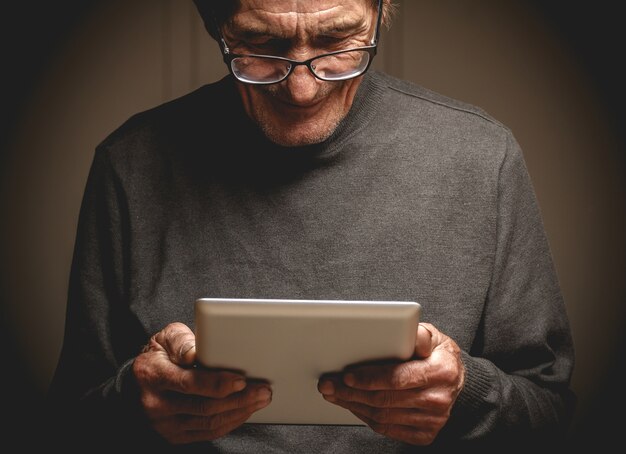 Elderly man with eyeglasses using a tablet