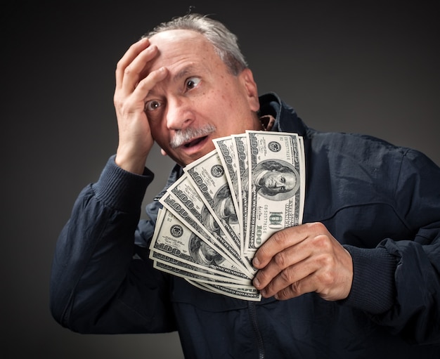 Photo elderly man with fan of dollars