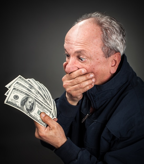 Elderly man with fan of dollars