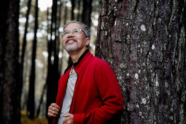 An elderly man with a gray beard lives and relaxes happily in the park.