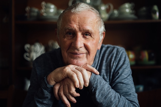 Elderly man with walking stick sitting at home