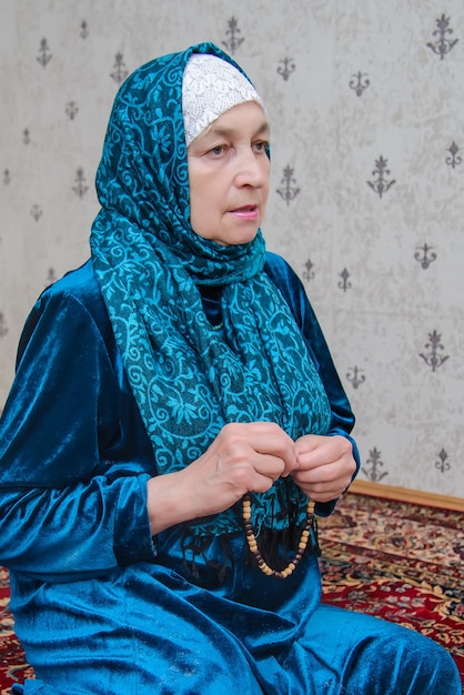 An elderly Muslim woman reads prayers