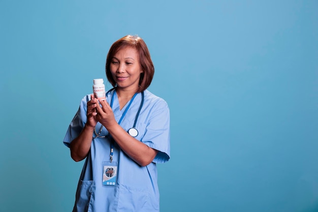 Elderly nurse holding antibiotic box reading medical leaflet\
during checkup visit consultation, working in health care industry.\
physician assistant planning medication treatment for sick\
patient