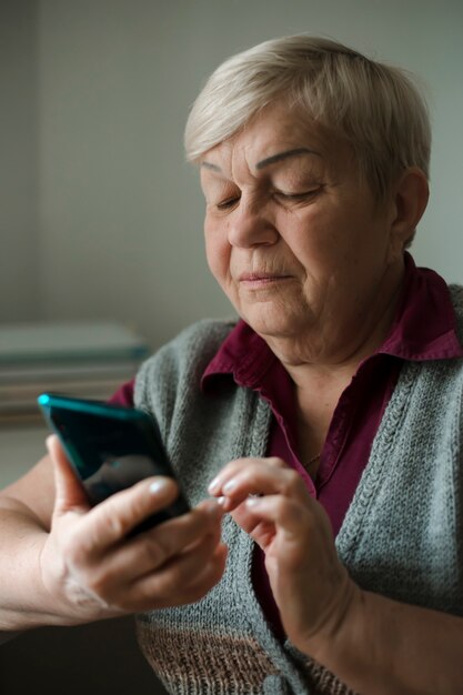 An elderly old woman uses a mobile phone.