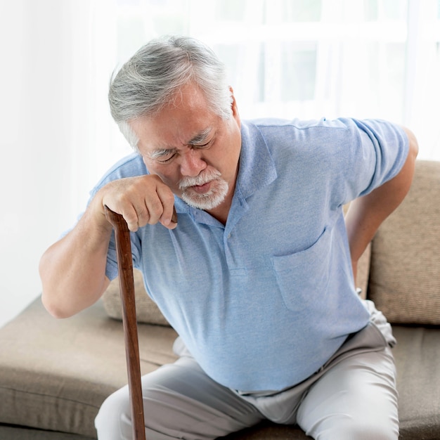 Elderly patients on couch , Asian senior man suffering from back pain  - medical and healthcare concept