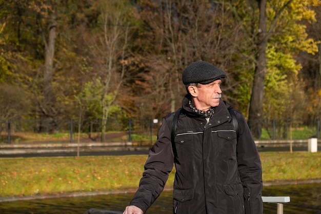 Elderly pensioner stands on beautiful autumn day in city park