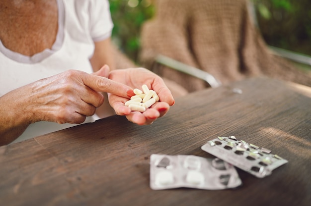 Le mani della donna anziana senior anziana che tengono le pillole delle vitamine delle droghe della medicina all'aperto nel giardino. concetto di lifestyle di persone anziane di assistenza sanitaria