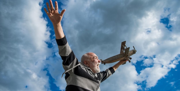 Elderly senior retired man mature man at retirement old man on sky background with toy plane