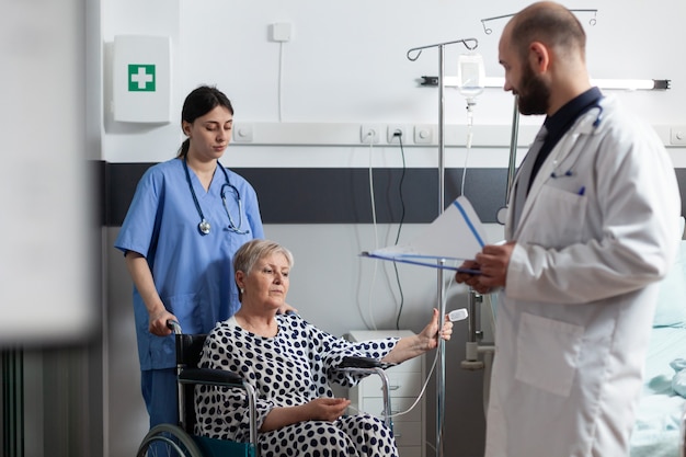 Elderly sick patient sitting in hospital wheelchair getting treatment