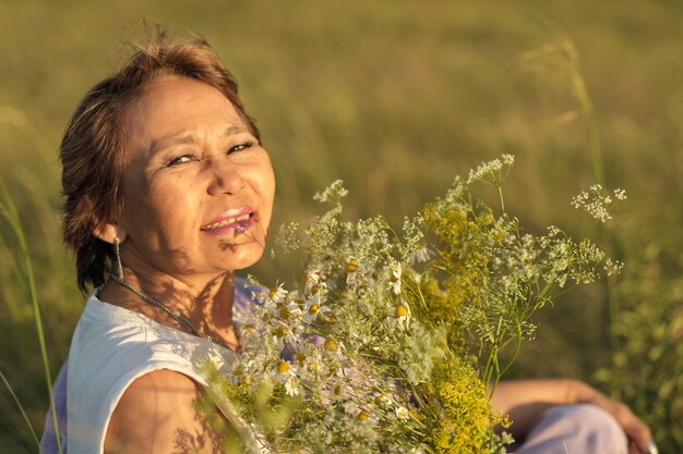밝은 햇살 속에서 야생 꽃의 향기를 호흡하는 노인이지만 여전히 매력적인 아시아 여성