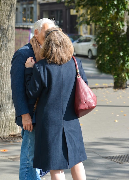 Elderly whitehaired couple kissing outdoors