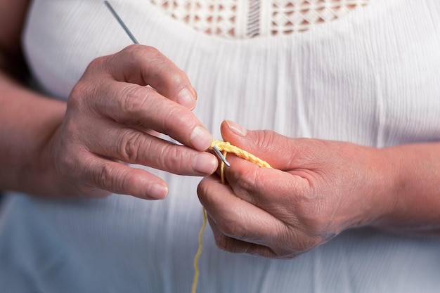 Elderly woman 60 year old latin grandmother knitting happy and comfortable inside her home