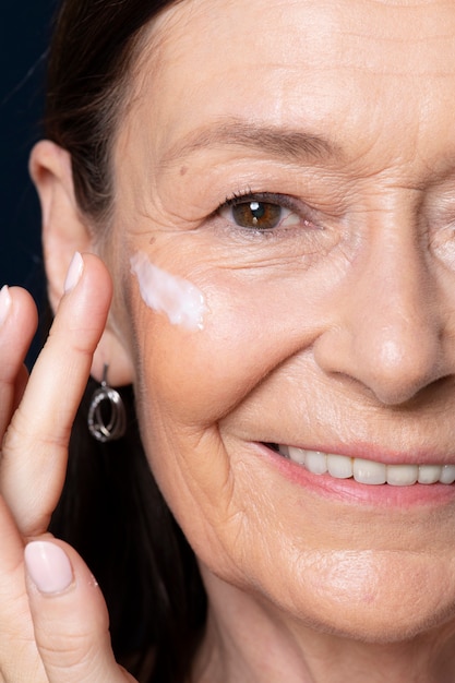 Elderly woman applying facial cream