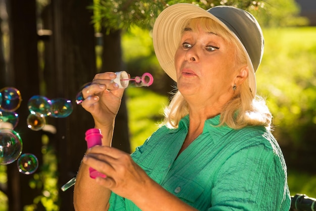 Photo elderly woman blowing bubbles