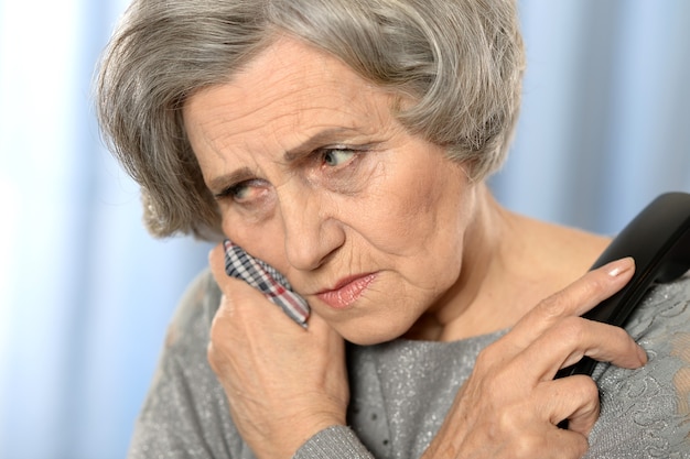 Elderly woman calling a doctor isolated on colored background