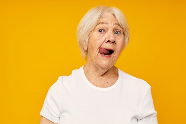 Elderly woman in casual tshirt gestures with his hands yellow background