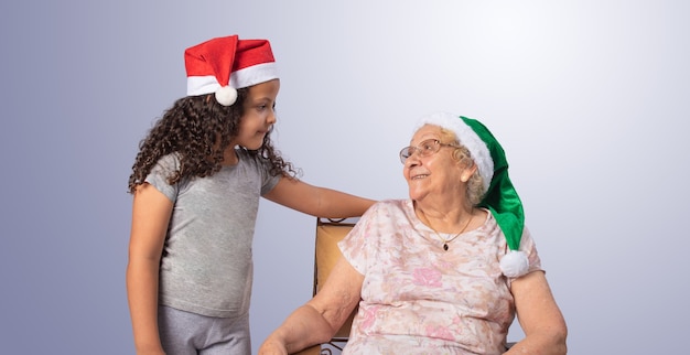 Elderly woman and child with Christmas hat on gray