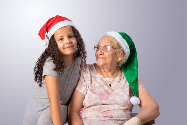 Elderly woman and child with Christmas hat on gray