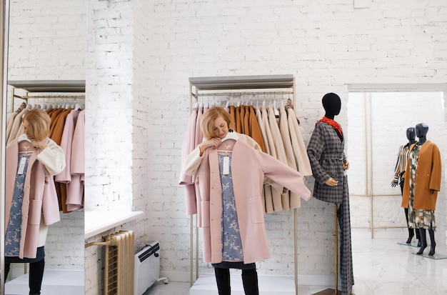 衣料品店の年配の女性がコートを選ぶ買い物で洋服を買う