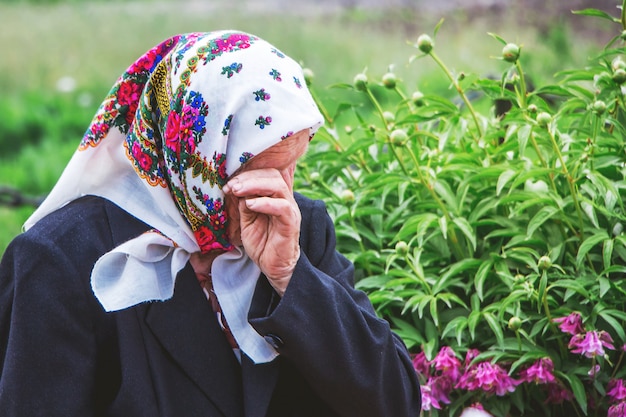 An elderly woman cries wiping her tears with her hand