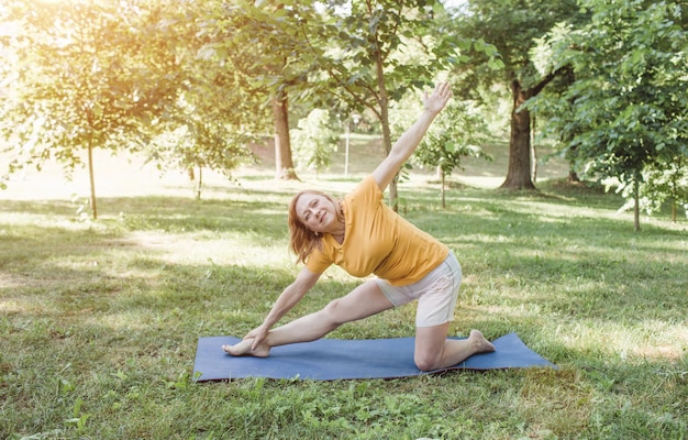 An elderly woman does yoga in the park to perform stretching for balance and balance