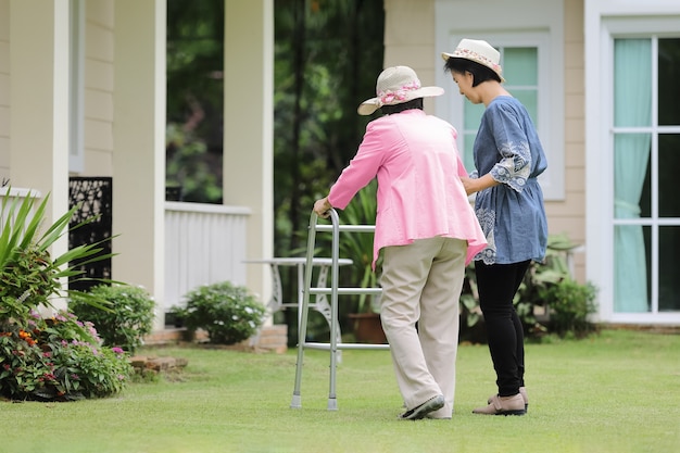 Elderly woman exercise walking in backyard with daughter