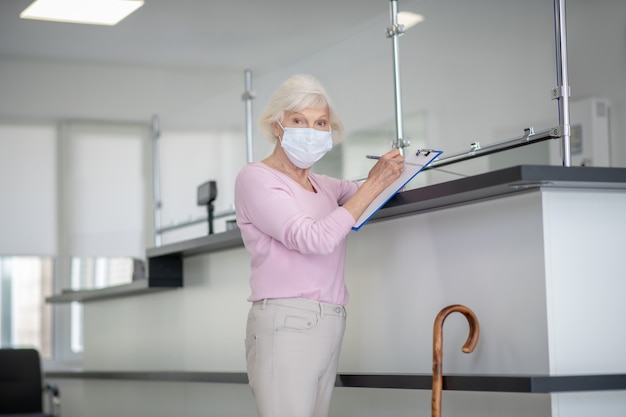 Elderly woman in a facial mask standing at the reception