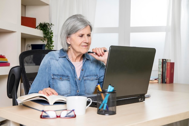 Donna anziana davanti a un computer portatile in una stanza