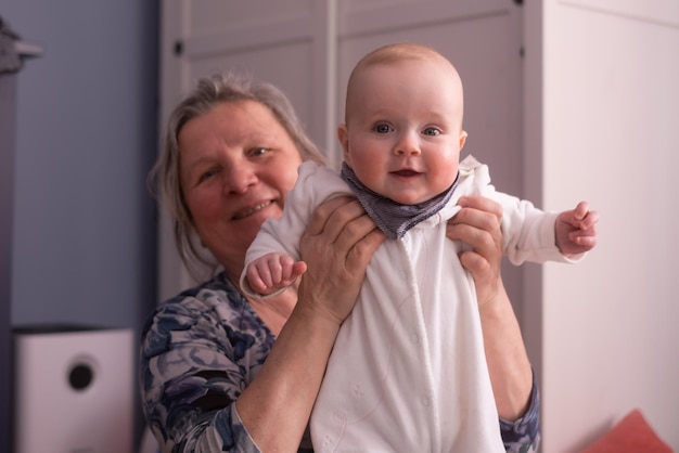 Elderly woman grandmother holding a month baby in her arms