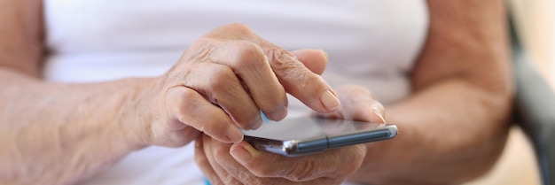 Elderly woman hand with smartphone texting at home chatting and using smartphone in retirement