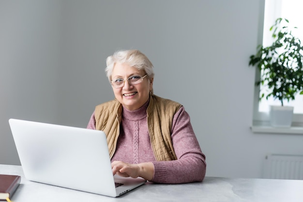 Elderly woman having a video call with her family, smiling and waving. Quarantine time.