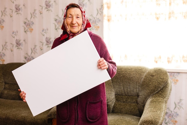 Donna anziana che tiene in mano una tela verticale vuota. cornice vuota per testo o foto. donna con poster mockup